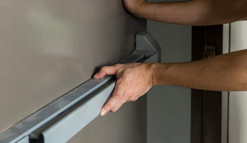 A close up photo showing someone pushing open a fire door.