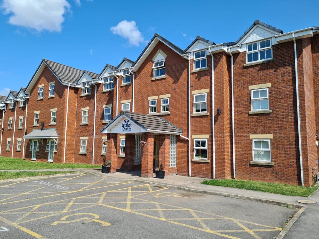 A photo of the exterior of a large care home, with disabled parking spaces outside the main entrance.